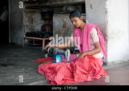 Indische Mädchen sitzen mit gekreuzten Beinen machen Kleider mit alten Nähmaschine am Schneiderei-Store in Jaipur, Rajasthan, Indien Stockfoto