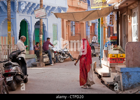 Straßenszene mit Indianerin gekleidet im roten Sari in die blaue Stadt Jodhpur, Rajasthan, Indien Stockfoto
