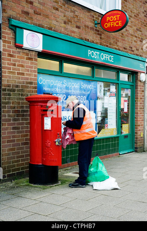 Postbote leeren Briefkasten außerhalb Postamt Stockfoto
