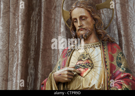 Das Christentum. Eine Statue von Jesus Christus. In dieser traditionellen katholischen Darstellung zeigt seine verletzte Hand auf symbolische Sacré Coeur. Stockfoto