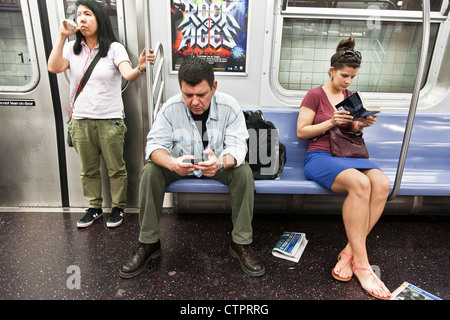 3 selbst absorbiert New York u-Bahn-Fahrgäste, ein Mann & 2 junge Frauen, jeweils in einer privaten Welt lesen SMS träumen absorbiert Stockfoto