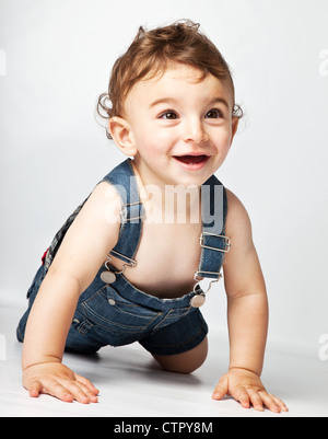 Glückliches Baby Boy kriechend auf Studioboden, schöne süße fröhliche Kind spielen indoor, gesundes Kind Freude Stockfoto