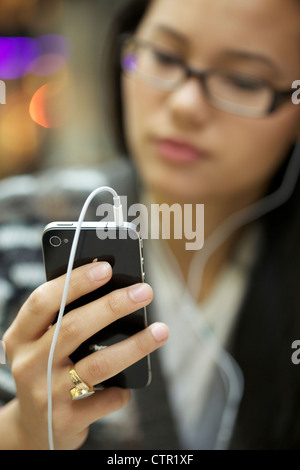 Junge Frau trägt Kopfhörer Musik hören mit ihrem Iphone 4 Stockfoto