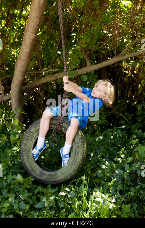 Junge auf eine Reifenschaukel schwingen. Stockfoto