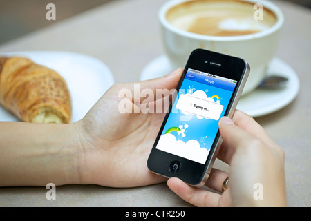 Nahaufnahme Bild von Frau Händchenhalten ein Iphone einloggen auf ihrem Twitter-Account in einem café Stockfoto