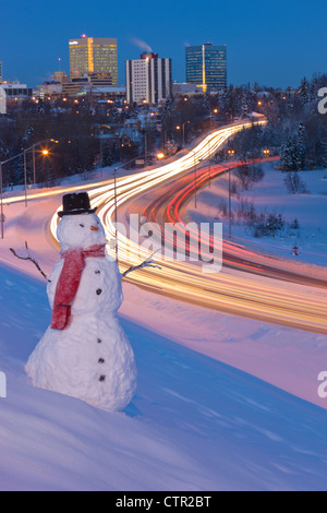Blick auf den Verkehr und die Innenstadt von Anchorage mit einem Schneemann im Vordergrund, Yunan Alaska Winter. Digital erweitert. Stockfoto