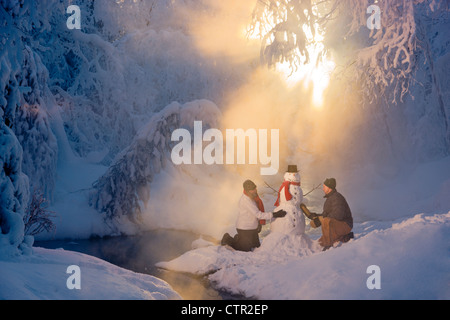 Mann Frau Schneemann in frostigen Wald Hintergrundbeleuchtung durch Sonnenstrahlen russische Jack Federn Park Yunan Alaska Winter bauen Stockfoto