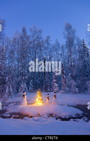 Schneemann Familie stehen nächsten Weihnachtsbaum auf Schnee bedeckte Insel in mittleren kleinen Bach in Raureif bedeckt Wald Dämmerung Stockfoto