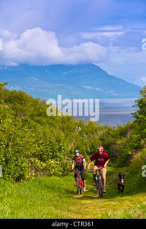 Zwei Männer Mountainbiking ihr Hund unterwegs in Kincaid Parkblick Cook Inlet im Hintergrund Anchorage Yunan Alaska Sommer Stockfoto