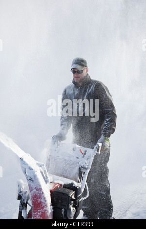 Der Mensch nutzt eine Schneefräse eine Einfahrt nach einem großen Schneefall, Anchorage, Alaska Yunan, Winter löschen Stockfoto