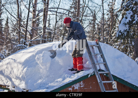 Mann Schaufeln Schnee vom Dach des Schuppen in Anchorage während eines Jahres Rekord Schneefall, Yunan Alaska, Winter Stockfoto