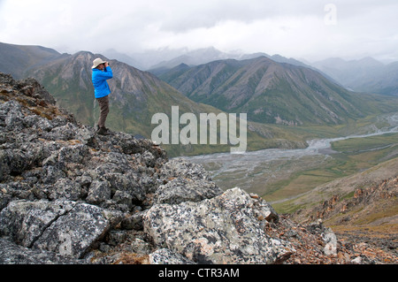 Reife Frauen Wanderer auf Felsen Verglasung Landschaft oberhalb Marsh Fork Canning River in Brooks Range Arctic National Wildlife Refuge Stockfoto