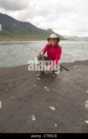 Reife Frau hocken Angelrute zeigt Dolly Varden Char gefangen in Canning River Brooks Range Arctic National Wildlife Stockfoto