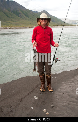 Reife Frau hocken Angelrute zeigt Dolly Varden Char gefangen in Canning River Brooks Range Arctic National Wildlife Stockfoto