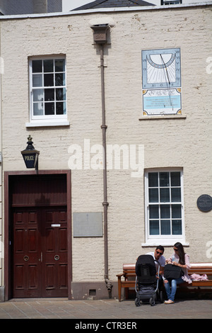 paar saß auf der Bank mit Baby im Kinderwagen vor der Polizeistation in St. Helier, Jersey im Juli Stockfoto