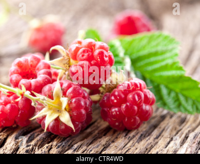 Himbeeren mit Blättern auf dem alten Holztisch. Stockfoto