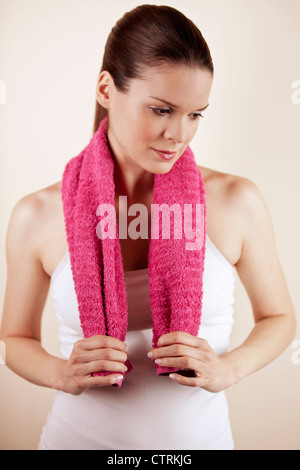 Eine junge Frau trägt Fitnesskleidung hält ein Handtuch Stockfoto