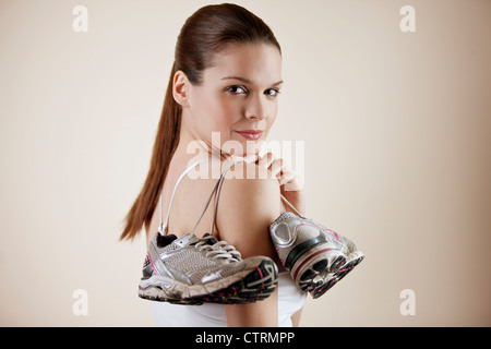 Eine junge Frau mit einem Paar Trainingsschuhe über die Schulter Stockfoto