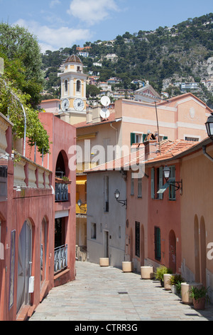 Stadt von Villefranche, Frankreich. Rue Henri Biais mit Turm aus dem 18. Jahrhundert St. Michaels Kirche im Hintergrund. Stockfoto