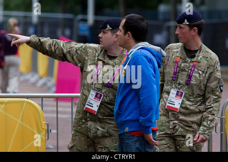 Soldaten der Königlichen Artillerie-regiment in der britischen Armee direkten Zuschauer während stehend bewachen den Eingang zum Volleyball Veranstaltungsort im Zentrum von London neben dem IOC-Ringe-Logo am 4. Tag der Olympischen Spiele 2012 in London. Weitere 1.200 Soldaten werden zum Sichern der Olympischen Spiele 2012 in London nach dem Scheitern von Sicherheit Fremdfirma G4S bieten genügend private Wachen eingesetzt. Das zusätzliche Personal wurden in inmitten weiter Ängste, die die private Sicherheit des Auftragnehmers Handhabung der £284m Vertrag bleibt ein Risiko für die Spiele erstellt. Stockfoto