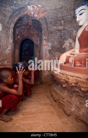 Myanmar, Burma. Bagan. Zwei junge Anfänger Mönche beten vor Buddha-Statue. Stockfoto