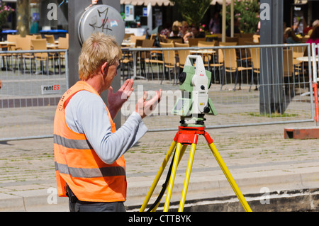 Geodät Land Surveyor Maßnahmen verfolgen Baustelle mit modernen aktuell Leica Theodolit in orange Signal farbige Weste Stockfoto