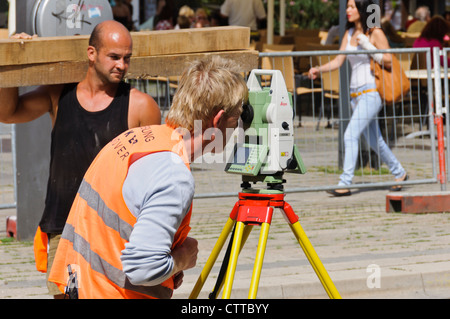 Geodät Land Surveyor Maßnahmen verfolgen Baustelle mit modernen aktuell Leica Theodolit tragen orange Signal farbige Weste Stockfoto