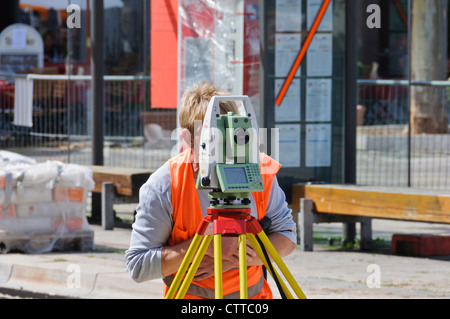 Geodät Land Surveyor Maßnahmen verfolgen Baustelle mit modernen aktuell Leica Theodolit mit farbigen Weste orange signal Stockfoto