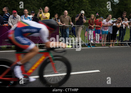 Ein Radfahrer fährt vorbei an Fans säumen die Route durch Bushy Park in Süd-west London, während der Olympischen Spiele London 2012 44km Herren Rad Zeitfahren, gewann schließlich durch Team GB Bradley Wiggins. Stockfoto