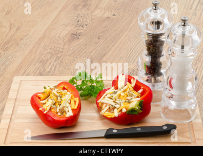 Zwei zubereitete frisch Paprika gefüllt und gewürzt mit geriebenem Käse und Reis auf einem Holzbrett Stockfoto