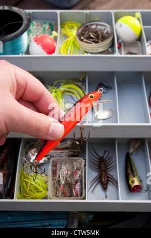 Ein Fischer wählt den richtigen Köder aus seinem Tackle Box, die er Fisch mit geht. Stockfoto