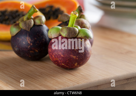 Drei frische tropische Mangostan auf Schneidebrett Stockfoto