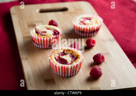 Drei Himbeer-Käsekuchen-Muffins mit frischen Himbeeren. Stockfoto