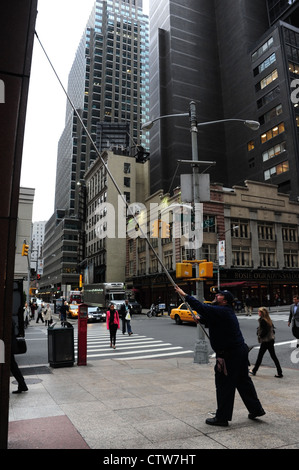 Bürgersteig Porträt Mann mit Teleskop Wischer reinigen Fassade Chase Bank, Ecke West 52nd Street und 7th Avenue, New York Stockfoto