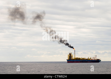 FPSO Bohrinsel im Offshore-Bereich, fern am Horizont.  Rauch aus dem Rohr bläst. Stockfoto