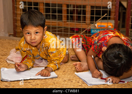 Myanmar, Burma. Bagan. Junge burmesische Mädchen schreiben in ihre Hefte. Thanaka einfügen, einen kosmetischen Sonnenschutz im Gesicht hat. Stockfoto