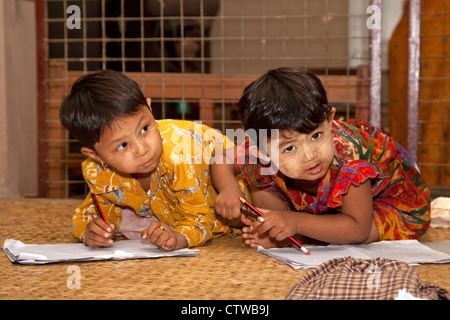 Myanmar, Burma. Bagan. Junge burmesische Mädchen schreiben in Notizbüchern. Sie haben Thanaka einfügen, eine kosmetische Sonnenschutzmittel auf ihren Gesichtern. Stockfoto