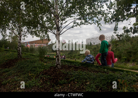 Junge Zuschauer bewundern die englischen Garten Blumen mit der wichtigsten Olympischen Stadion und Basketball-Arena im Hintergrund während der Olympischen Spiele 2012 in London. Londoner Olympiapark, in knapp einer Quadratmeile ist der größte neue Park in der Stadt seit mehr als 100 Jahren. Die Anpflanzung von 4.000 Bäume, 300.000 Feuchtgebietspflanzen und mehr als 150.000 Stauden sowie nektarreichen Wildblumen sorgen für eine farbenfrohe Kulisse für die Spiele. Stockfoto