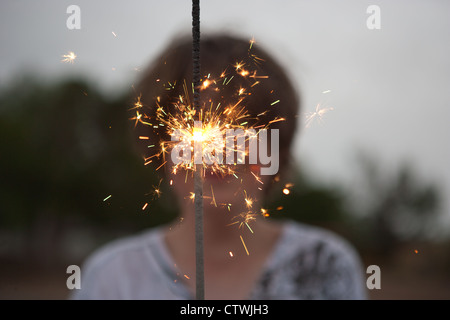 13 Jahre alter Junge hält eine große Spakler am 4. Juli. Stockfoto