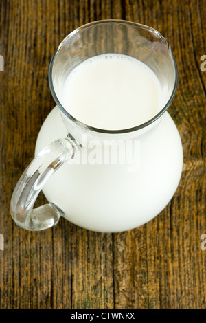 Krug mit Milch auf alten Holztisch Stockfoto