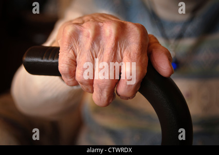 Ältere Frau ist Händen umklammert einen Spazierstock faltig. Stockfoto