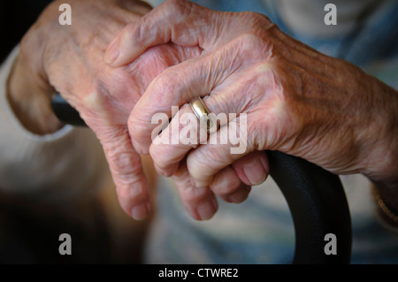 Ältere Frau ist Händen umklammert einen Spazierstock faltig. Stockfoto