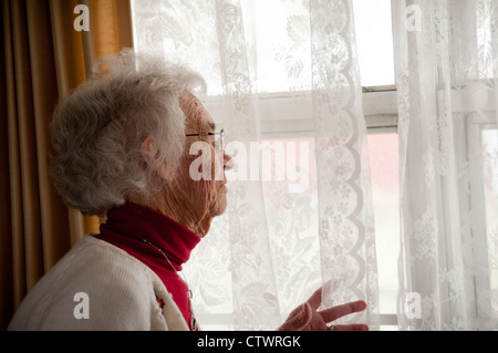 Ältere Frau aus Fenster Stockfoto
