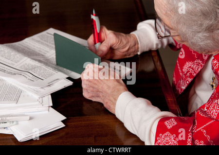 Ältere Frau ausstellen eines Schecks und persönliche Finanzen Rechnungen bezahlen Stockfoto