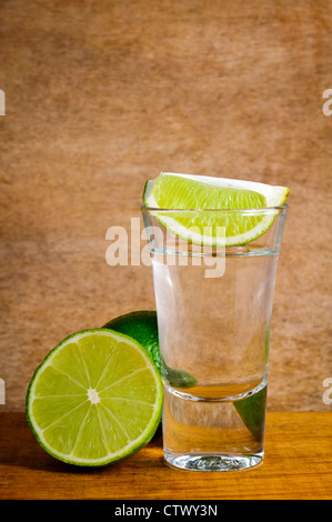 Tequila shot und Kalk auf einem hölzernen Hintergrund Stockfoto