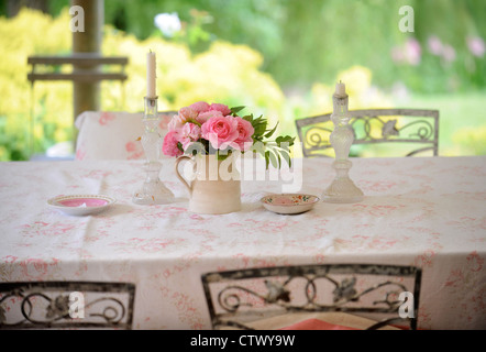 Glas-Leuchter und rosa Rosen auf einem Tisch UK Stockfoto