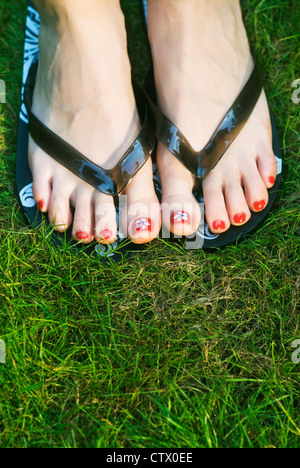 Ein paar pedikürten Füße mit hübschen Zehennägeln tragen Flip-Flops. Stockfoto