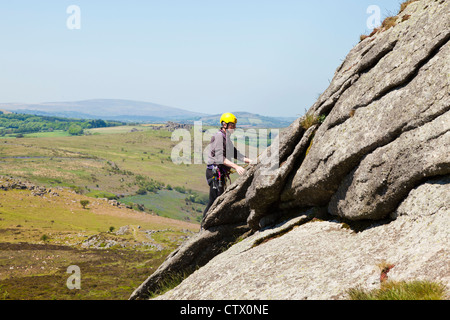 Mann, Klettern auf Haytor Rocks, eine Granit-Tor auf Dartmoor, Devon, UK Stockfoto