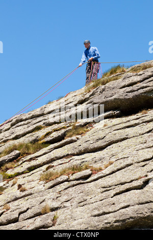 Moderator hilft anderen Bergsteiger auf Haytor Rocks, eine Granit-Tor auf Dartmoor, Devon, UK Stockfoto