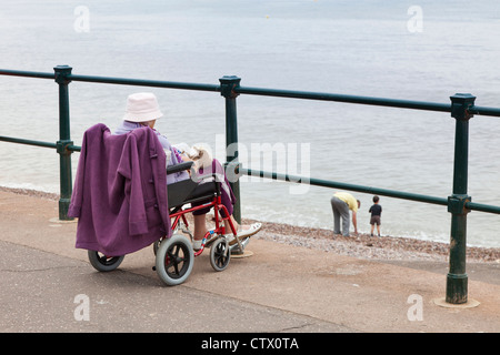 Eine alte Dame im Rollstuhl am Strand von Sidmouth, Devon, UK Stockfoto